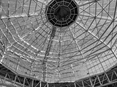 Glass dome of a modern building. View from the inside of the room. Light construction of transparent roof made of round steel tubes. Architectural background. Glass dome from inside at skyscrapper background