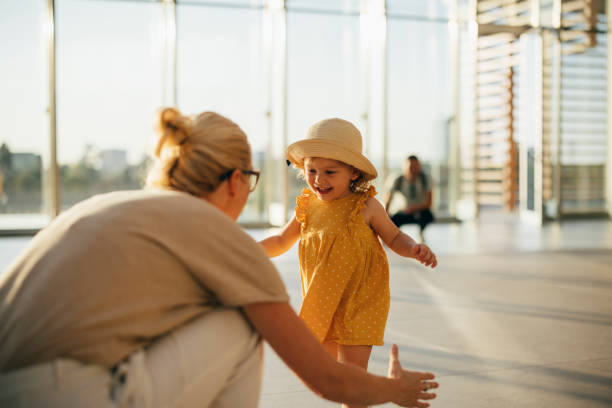 An Anonymous Mother Greeting her Daughter and Husband at Airport Cheerful smiling girl running to her unrecognizable mom after vacation with a dad baby squatting stock pictures, royalty-free photos & images