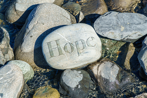 engraved stone rock with the word HOPE is stream