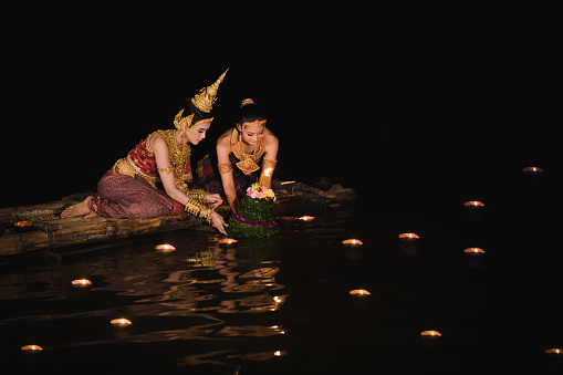 beautiful two woman thailand wearing thai traditional dress on bamboo for river park garden in night loy krathong festival day