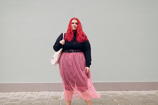 Plus size overweight fat body positive lgbtq woman with red hair and pink glasses.