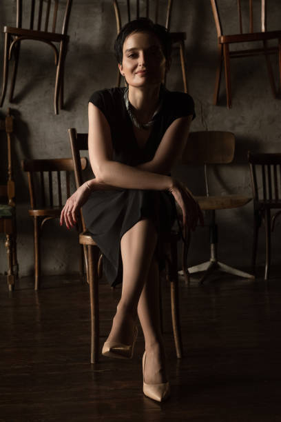 istock Pretty brunette woman sits on chair posing on camera 1352767785