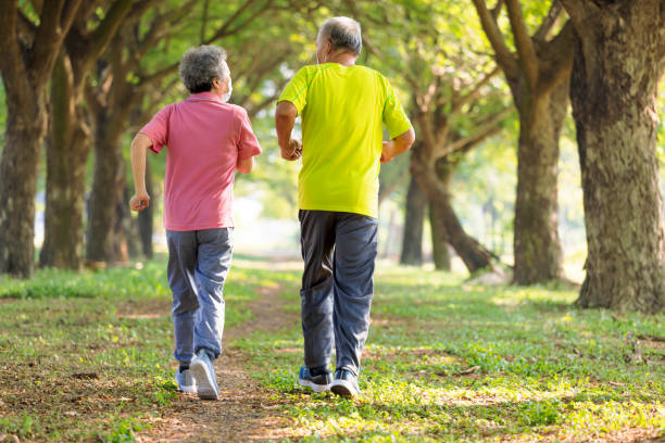 Rear view of Senior couple in face mask and jogging in the park stock photo