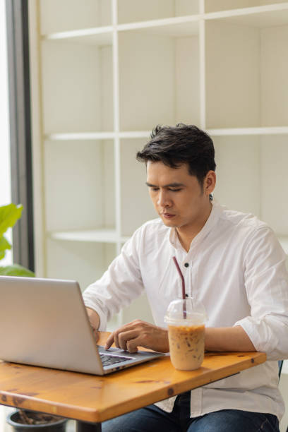 istock Young Asian men, future students for self or personal learning ideas. Online students at coffee shops with books and laptops. 1352774741