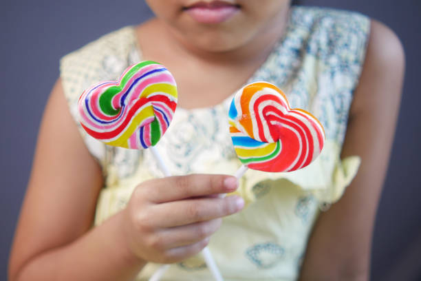 istock child girl hand hold rainbow heart shape candy 1352780275