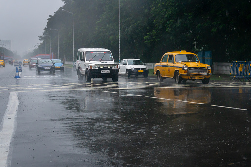 Kolkata, West Bengal, India - 17th August 2019 : Image shot through raindrops falling on wet glass, cars waiting in traffic signal - monsoon stock image of Kolkata (formerly Calcutta) city ,