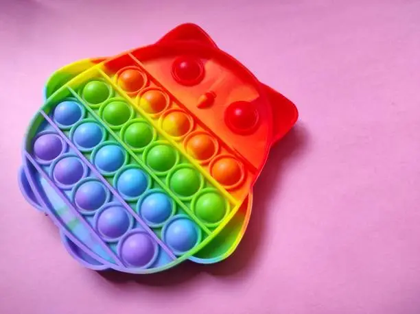 Photo of Rainbow color Pop it toy on a pink background