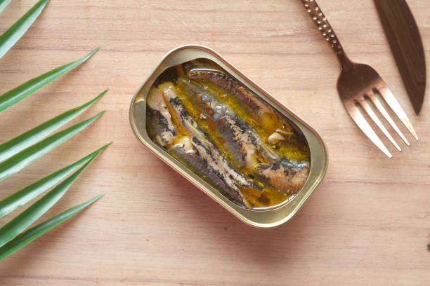 istock open tin of sardines on white tiles background. 1352784131