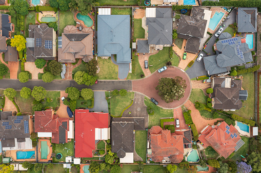 Top down aerial view of a residential cul-de-sac with houses, pools and gardens in suburban Sydney, Australia.