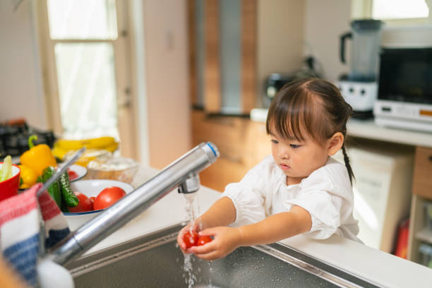 istock Small girl washing vegetables by herself in kitchen 1352791487