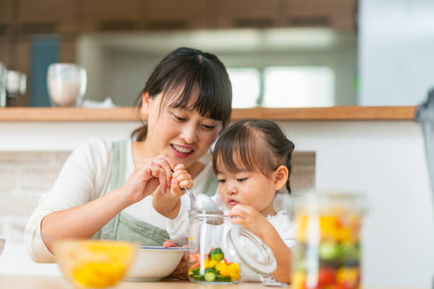 mother and her small daughter preparing salad at home. mother helping her small daughter preparing vegetables and encouraging her for healthy eating - salad japanese culture japan asian culture imagens e fotografias de stock