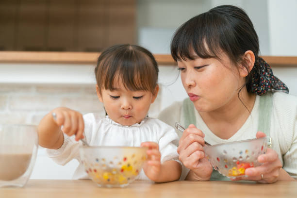 mãe e sua filha pequena desfrutando de comer salada e beber smoothie em casa - salad japanese culture japan asian culture - fotografias e filmes do acervo