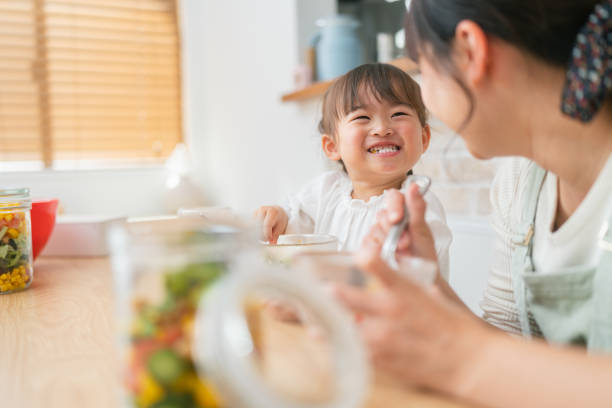 mother and her small daughter enjoying eating salad and drinking smoothie at home - salad japanese culture japan asian culture imagens e fotografias de stock
