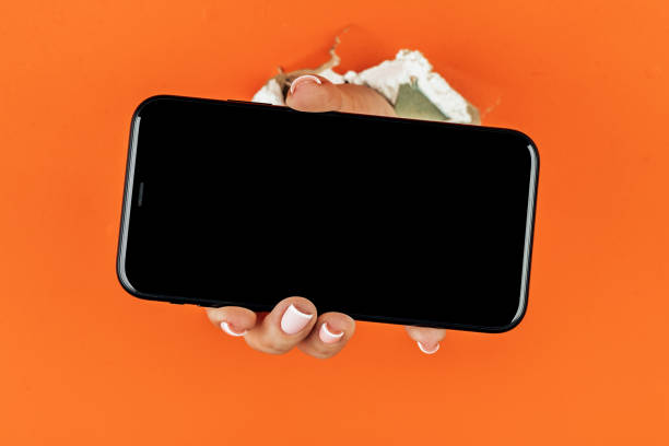 istock A woman holds a phone through ragged orange drywall 1352805006