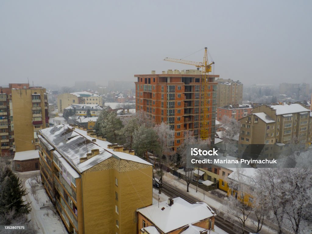 City view on a snowy winter day Ivano-Frankivsk City view on a snowy winter day with fog. Tower crane and building construction site at day. New construction site with crane. Building background. Architecture Stock Photo