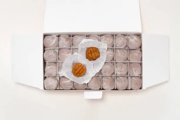 Photo of Small walnut-flavored cakes in the size and shape of a walnut in the packing box. Isolated on white background. Top view.