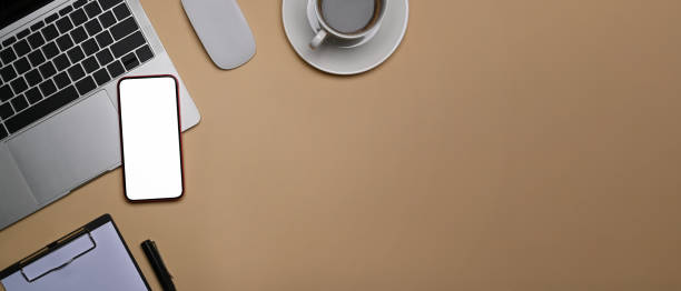istock Top view smart phone with blank screen, laptop computer and coffee cup on beige background. 1352809756