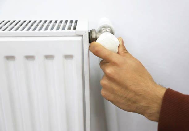 istock heater radiator valve. a man adjusting the radiator valve 1352810823