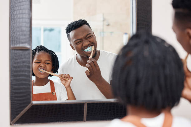 foto de un joven padre que se une a su hija mientras se cepillan los dientes en el baño de casa - brushing teeth fotografías e imágenes de stock