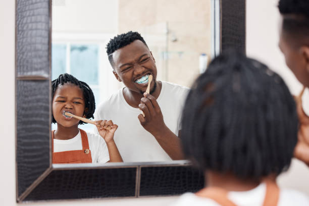 scatto di un giovane padre che lega con sua figlia mentre si lavano i denti nel bagno di casa - vitality innocence clothing human age foto e immagini stock