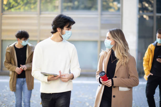 istock Happy college students, wearing a masks, walking together on campus 1352814413