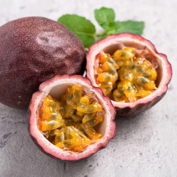 Close up of delicious juicy fresh passion fruit on gray table background.