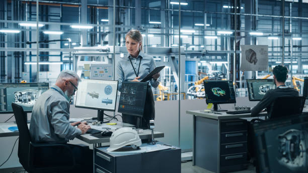istock Car Factory: Diverse Team of Automotive Engineers Working, Using Computers to Design Advanced Models for High-Tech Engines. Automated Robot Arm Industrial Assembly Line Manufacturing Electric Vehicles 1352825055