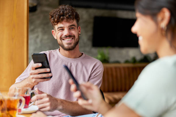 istock Happy couple using mobile phones in a cafe. 1352825593