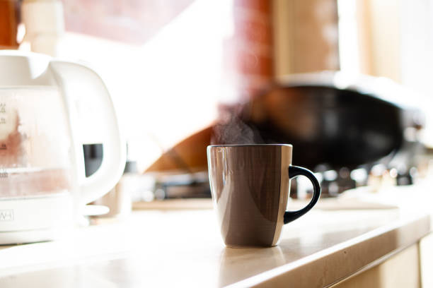 Brown coffee cup on kitchen table with real natural daylight and steam, coffee mug in beige home interior