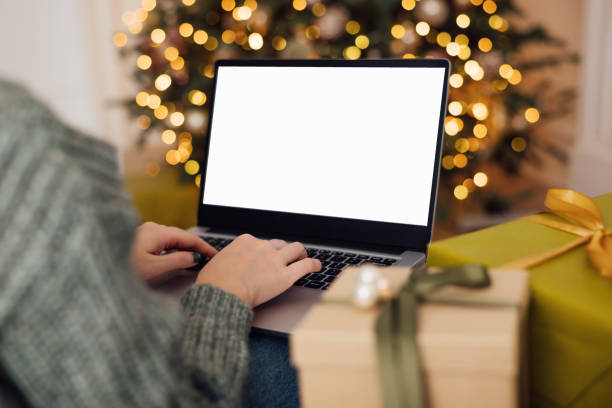 istock woman work on laptop computer with blank display screen with mockup copy space. home interior decorated for Christmas celebration with Christmas tree and garland lights. 1352831840