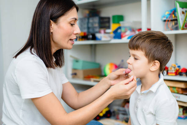istock A woman speech therapist deals with a boy and does an exercise to correct the speech apparatus using a straw or spaghetti 1352831908