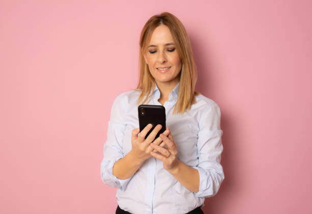 istock Smiling business woman using smartphone over white background. 1352832230