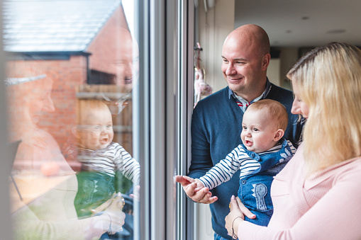 Happy family of three smiling and looking out of the window - Happy little boy with mother and father enjoying time together and having fun - Lifestyle and family concepts