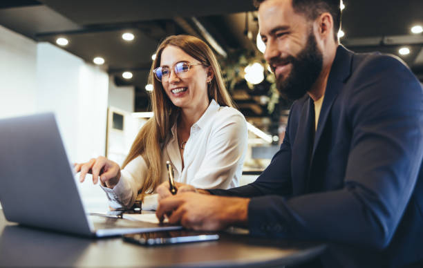 cheerful businesspeople using a laptop in an office - cheerful happiness men women imagens e fotografias de stock