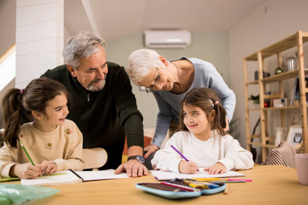 istock Senior couple assisting to their granddaughters while doing homework 1352834475