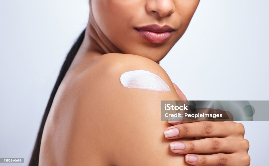 Cropped shot of an unrecognizable woman applying moisturiser to her shoulder against a grey background Lotion like a potion Moisturizer Stock Photo