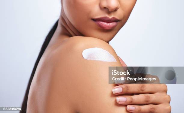 Cropped Shot Of An Unrecognizable Woman Applying Moisturiser To Her Shoulder Against A Grey Background Stock Photo - Download Image Now