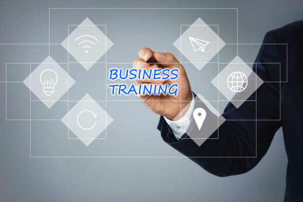 istock Man pointing at virtual screen with inscription BUSINESS TRAINING on light background, closeup 1352841337