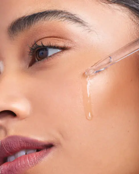 Photo of Cropped shot of a young beautiful woman applying serum to her face