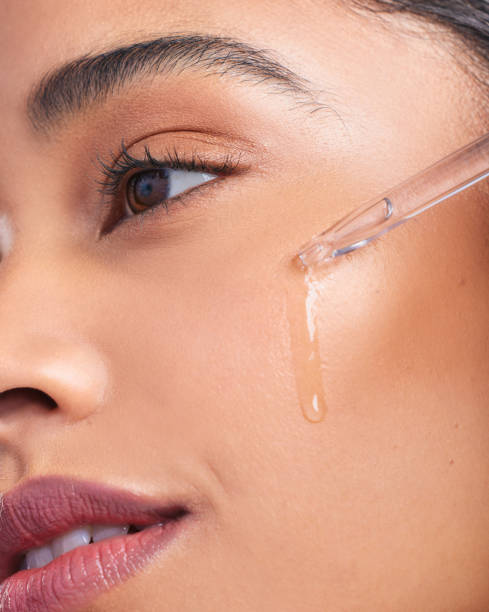 cropped shot of a young beautiful woman applying serum to her face - tratamento de pele imagens e fotografias de stock