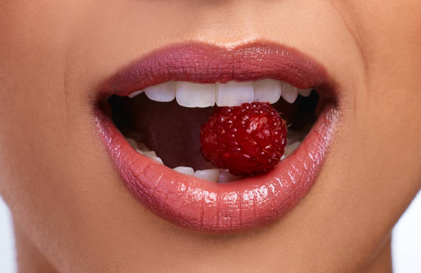 istock Cropped shot of an unrecognizable woman's perfect teeth biting on a raspberry 1352843163