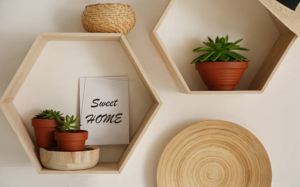 istock Hexagon wooden shelves with beautiful plants and decorative elements on light wall 1352844231