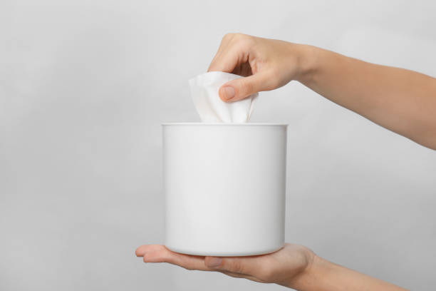 istock Woman taking paper tissue from holder on light background, closeup 1352846253