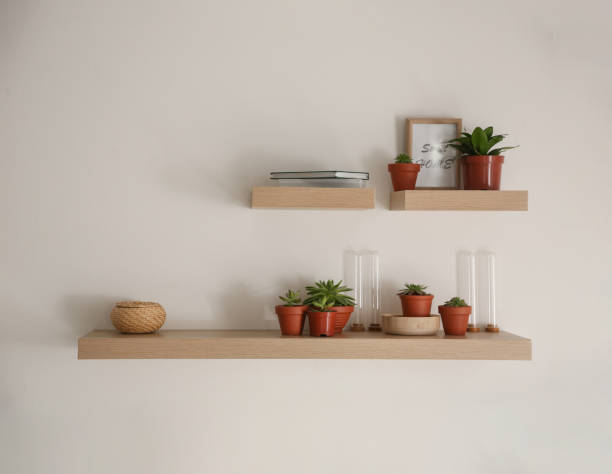 istock Wooden shelves with beautiful plants and different decorative elements on light wall 1352847126