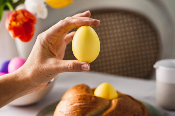 hand einer frau mit gelb gefärbtem osterei - breakfast easter yellow easter egg stock-fotos und bilder