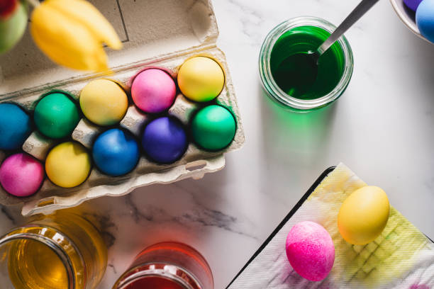 Coloring eggs with natural dye for Easter Easter eggs are painted with natural egg dye. Colorful Easter eggs in a carton with multicolored dye in glass bottles over the table. easter egg coloring stock pictures, royalty-free photos & images