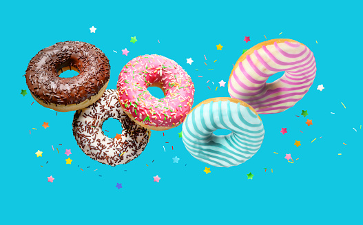 Various donuts falling with sprinkles over turqouise blue background background.