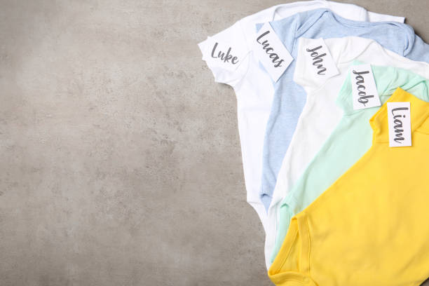istock Bodysuits with different baby names on grey background, flat lay. Space for text 1352849011