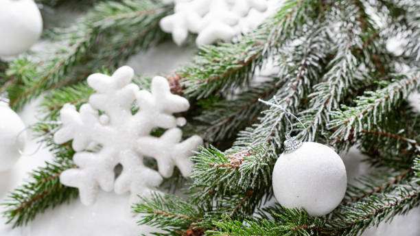 istock Close up of Christmas white decorations and green branches on light surface 1352850793