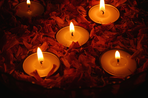Close-up of burning Tea light candles and fresh marigold flower petals in a bowl filled with water